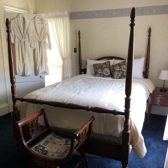 A bed room with four poster bed and chair