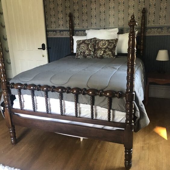 A bed with a wooden frame and white sheets.